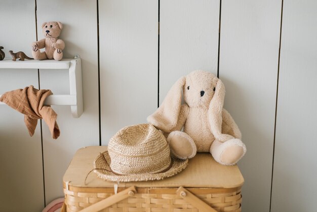 Juguete de peluche, un conejo de peluche o un conejo y un sombrero de paja en la decoración de una habitación infantil de estilo escandinavo o minimalista.