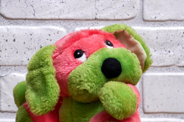 Foto juguete de peluche multicolor para niños en el fondo de la pared de ladrillo