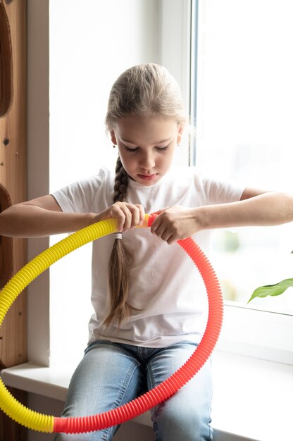 Juguete plástico de tubo de pop sensorial antiestrés en manos de niños. una niña pequeña feliz juega con un juguete poptube fidget en casa. niños sosteniendo y jugando pop tube color amarillo y rojo, tendencia 2021 año