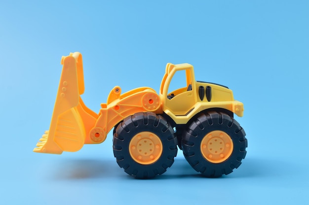 Foto juguete de tractor retroexcavadora de plástico de construcción aislado en un fondo azul