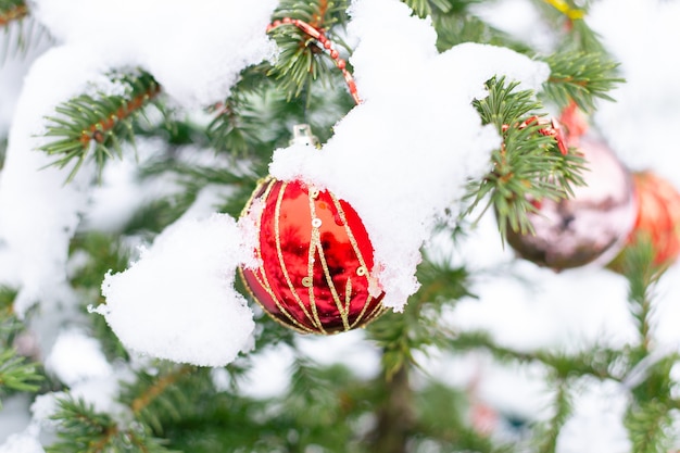 Juguetes de Año Nuevo en un árbol de Navidad al aire libre en invierno bajo la nieve.