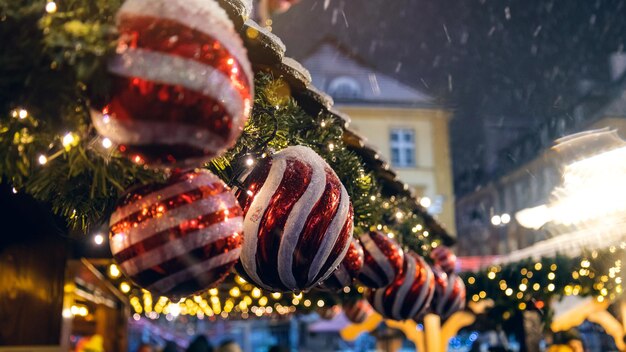 Juguetes de año nuevo por la noche en la visera. Fondo de Navidad. Ramas verdes de un árbol de Navidad iluminado por lámparas brillantes