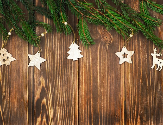 Juguetes de árbol de Navidad de madera sobre un fondo de madera con ramas de abeto. Fondo festivo,