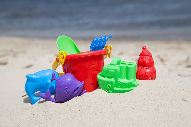 Foto juguetes de arena en la playa cerca del agua.