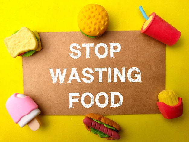 Juguetes de comida rápida y cartón marrón con la palabra STOP WASTING FOOD