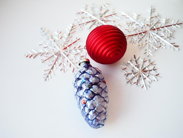 Juguetes y decoraciones de árbol de Navidad y Año Nuevo sobre un fondo blanco Un cono de vidrio azul violeta con nieve blanca decorativa en la parte superior Bola de Navidad de rayas rojas Copos de nieve plateados