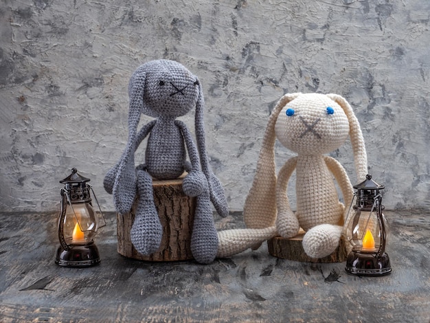 Juguetes hechos a mano amigurumi conejitos de ganchillo sentados en tocones y linternas encendidas