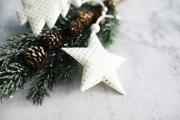 Juguetes hechos a mano de árbol de hoja perenne, copos de nieve, globos y rama de abeto sobre fondo de piedra, tarjeta de felicitación de Navidad con espacio para texto deseo