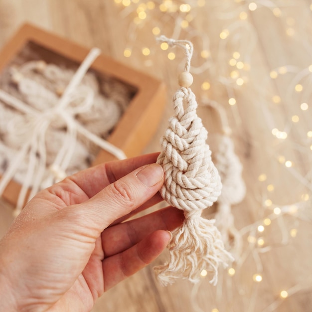 Foto juguetes de macramé de árbol de navidad en boad de madera materiales naturales hilo de algodón cuentas de madera y palo decoraciones ecológicas adornos decoración hecha a mano vacaciones de invierno y año nuevo