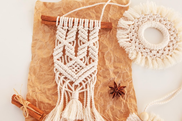 Juguetes de macramé de Navidad en papel artesanal Fondo blanco Materiales naturales Hilo de algodón Cuentas de madera y palo Adornos de decoración ecológica Decoración hecha a mano Vacaciones de invierno y año nuevo