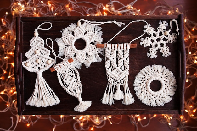 Juguetes de macramé de Navidad sobre fondo oscuro Materiales naturales hilo de algodón cuentas de madera y palo Decoraciones ecológicas adornos decoración hecha a mano Vacaciones de invierno y año nuevo