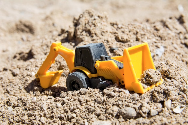 Juguetes de maquinaria de construcción en la arena en un día soleado Juguetes de construcción de juguetes de colores amarillo y negro