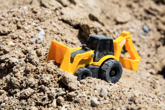 Juguetes de maquinaria de construcción en la arena en un día soleado Juguetes de construcción de juguetes de colores amarillo y negro