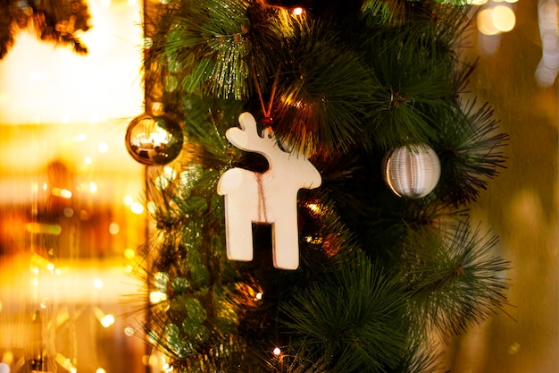 Juguetes de Navidad bolas de oro de ciervos de madera y de guirnalda en ramas de abeto para la decoración de Año Nuevo