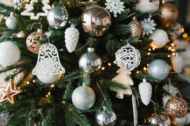 Juguetes de Navidad dorados, plateados y blancos en el primer plano del árbol de Navidad Fondo festivo para espacio de copia