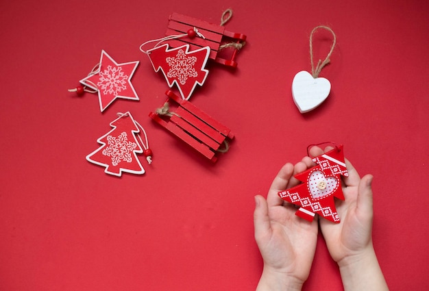 Juguetes de Navidad naturales hechos a mano sobre fondo rojo. Manos de niño con juguete de Navidad