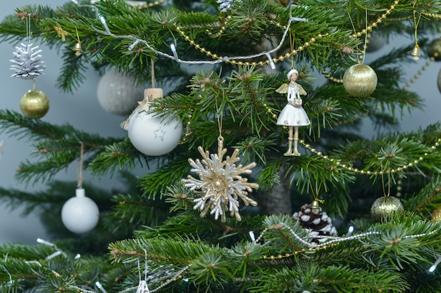 Juguetes de Navidad de oro blanco y argent colgando del árbol