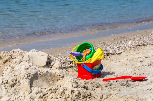 Juguetes para niños en la playa de arena contra el mar