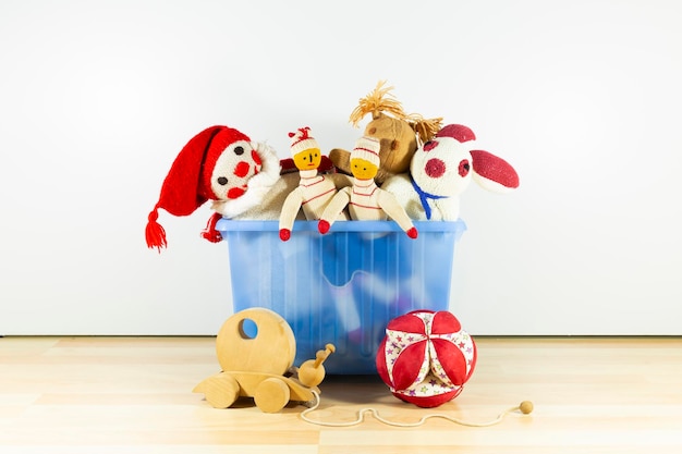 Foto juguetes de niños vintage lindos y divertidos en una caja de plástico azul frente a una pared blanca