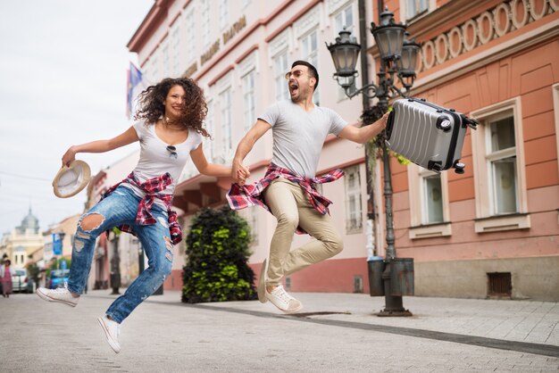 Juguetón feliz pareja joven está saltando por la calle y riendo.