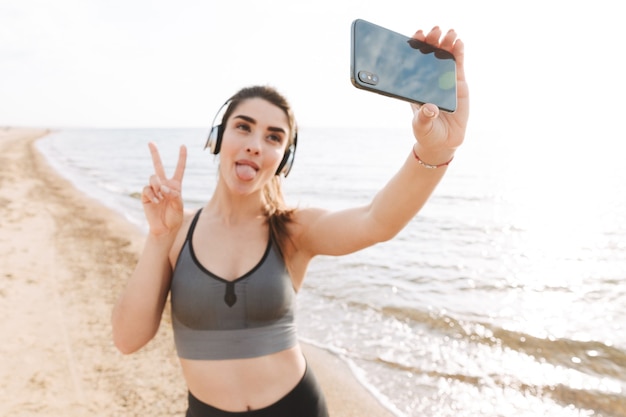 Juguetón joven deportista de pie en la playa.