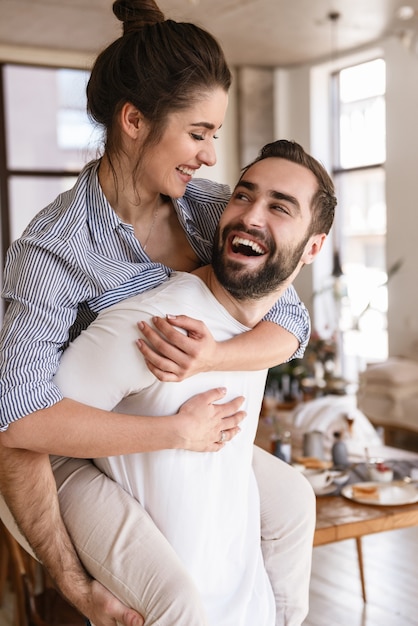 Juguetón morena pareja enamorada hombre y mujer sonriendo mientras se abrazan juntos en el apartamento