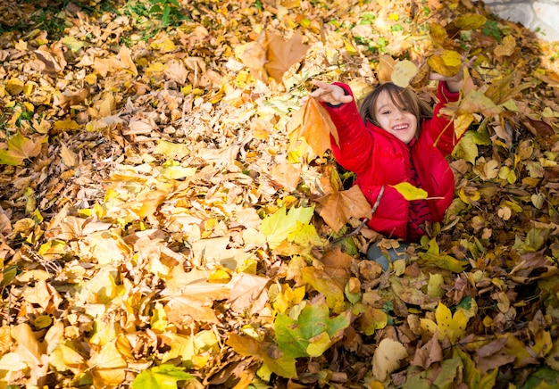 Juguetón niño feliz en otoño deja en el parque