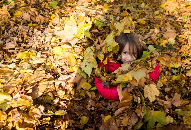 Juguetón niño feliz en otoño deja en el parque