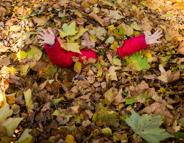 Juguetón niño feliz en otoño deja en el parque