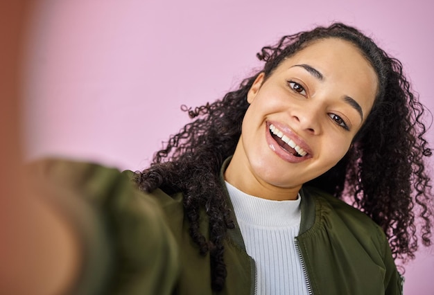 Juguetón nunca pasará de moda Captura de una atractiva mujer joven de pie sola contra un fondo rosa en el estudio y tomando una selfie