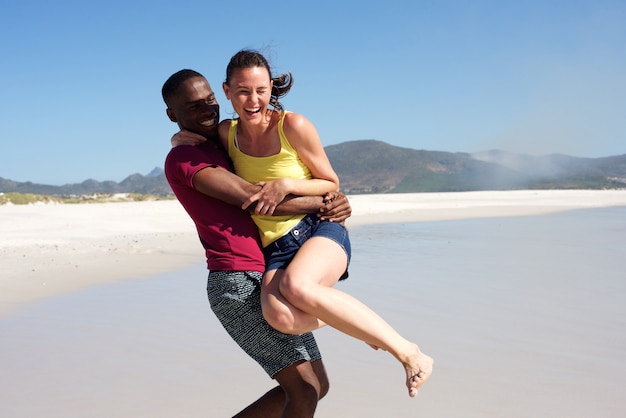 Juguetón pareja joven divirtiéndose al aire libre en la playa