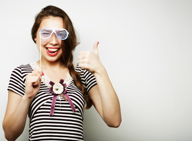 Foto juguetonas mujeres jóvenes sosteniendo una fiesta gafas.