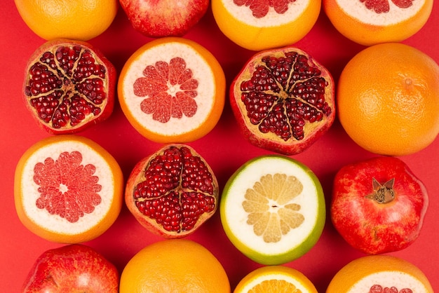 Juicy pomelo naranja granada cítricos cariño sobre fondo rojo.