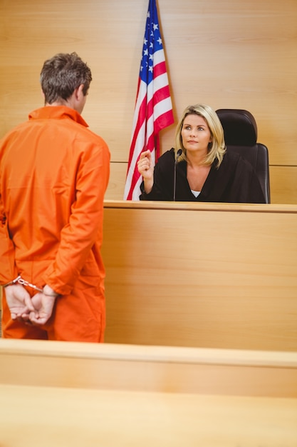 Foto juiz e criminoso falando na frente da bandeira americana