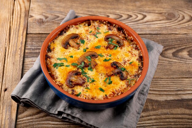 Juliana con patatas y champiñones en una fuente para horno sobre un fondo de madera