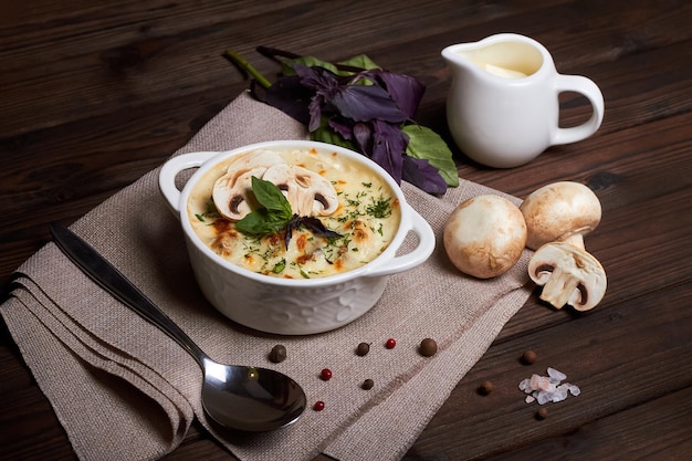 Juliana de pollo con queso, champiñones y hierbas en plato blanco sobre tabla de madera