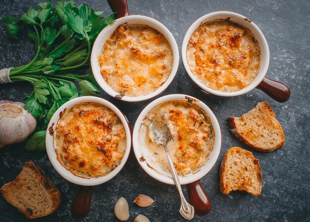 Julienne em porções, cogumelos com creme e queijo, comida de restaurante em um fundo escuro