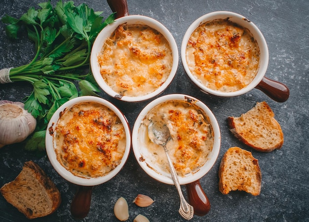 Julienne in Portionen, Pilze mit Sahne und Käse, Restaurantessen auf dunklem Hintergrund