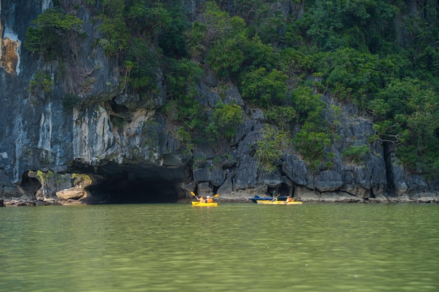 Juncos turísticos flutuando entre rochas calcárias na Baía de Ha Long, pessoas andando de caiaque dentro de uma caverna na Baía de Lan Ha, perto da Baía de Halong, Vietnã