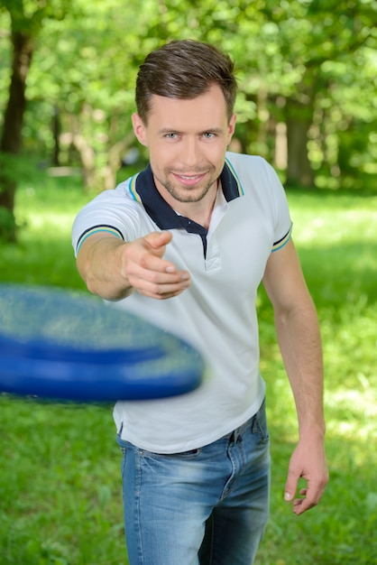 Jung und gutaussehender Mann, die Frisbee im Park spielen