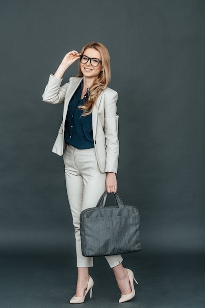 Jung und klug. In voller Länge selbstbewusste junge Frau in eleganter Freizeitkleidung, die ihre Brille anpasst