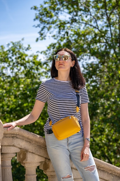 Junge 30-jährige Frau in Jeans-T-Shirt und gelber Tasche, die in einem Park spazieren geht Ciutadella in Barcelona Mädchen reisen in Spanien