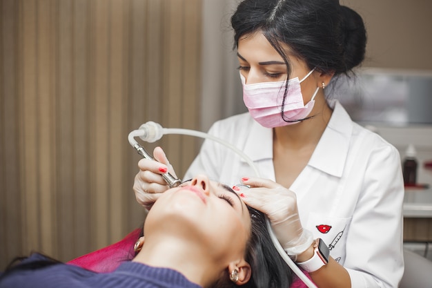 Junge Ärztin, die Facelifting-Vorrichtungsverfahren macht