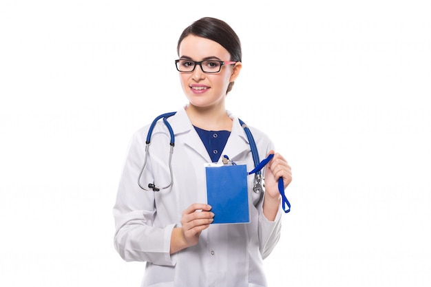 Junge Ärztin mit dem Stethoskop, das blauen Ausweis in ihren Händen in der weißen Uniform auf Weiß hält