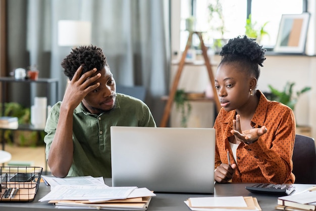 Junge afrikanische Frau und Mann, die auf den Laptopbildschirm schauen