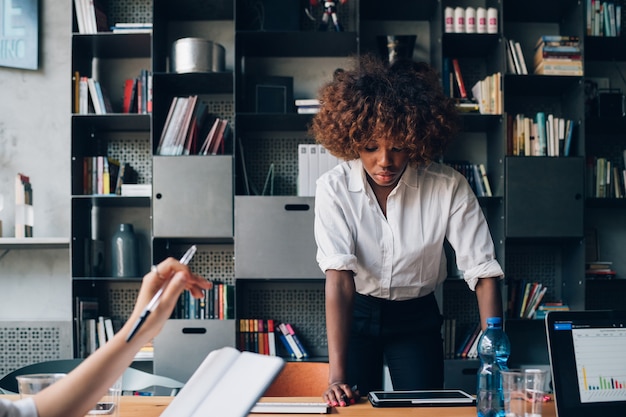 Junge afrikanische Geschäftsfrau, die in coworking Büro mit Kollegen arbeitet