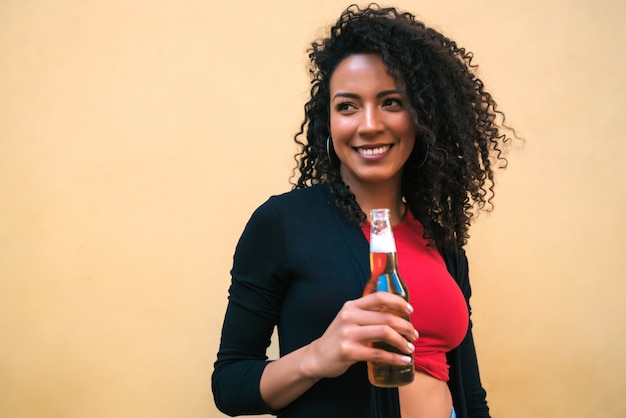 Junge afro-frau, die bier trinkt