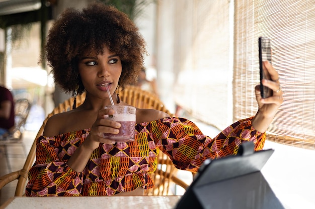 Junge afro-frau, die ein selfie mit ihrem handy in einem restaurant macht