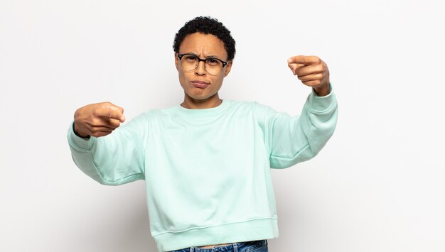 Junge Afro-Frau, die mit beiden Fingern und wütendem Gesichtsausdruck nach vorne zeigt und Ihnen sagt, Sie sollen Ihre Pflicht tun