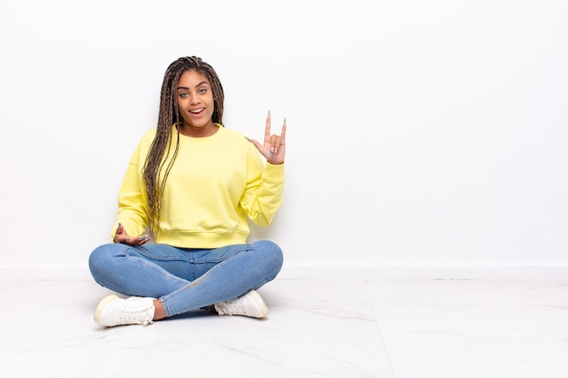 Junge Afro-Frau, die sich glücklich, lustig, selbstbewusst, positiv und rebellisch fühlt